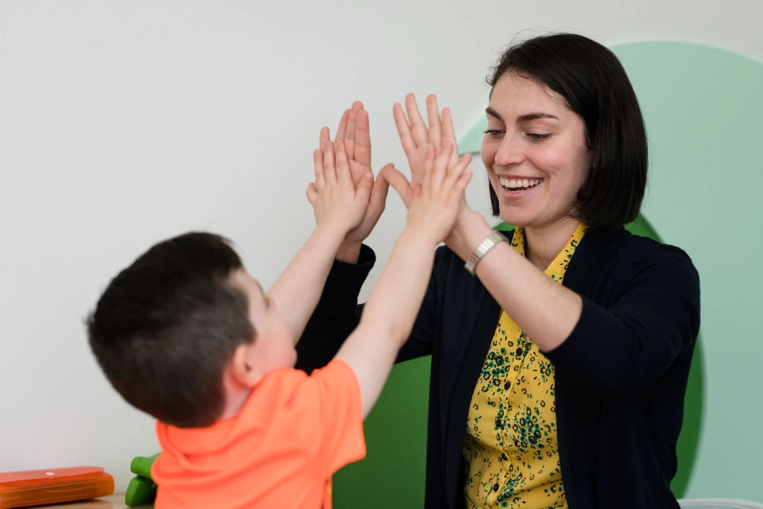A CST Academy therapist and child celebrating progress with a high-five